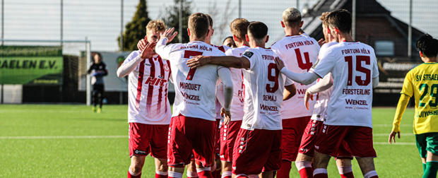 Die Mannschaft von Fortuna Köln bildet eine Jubeltraube auf dem Fußballplatz beim SV Straelen